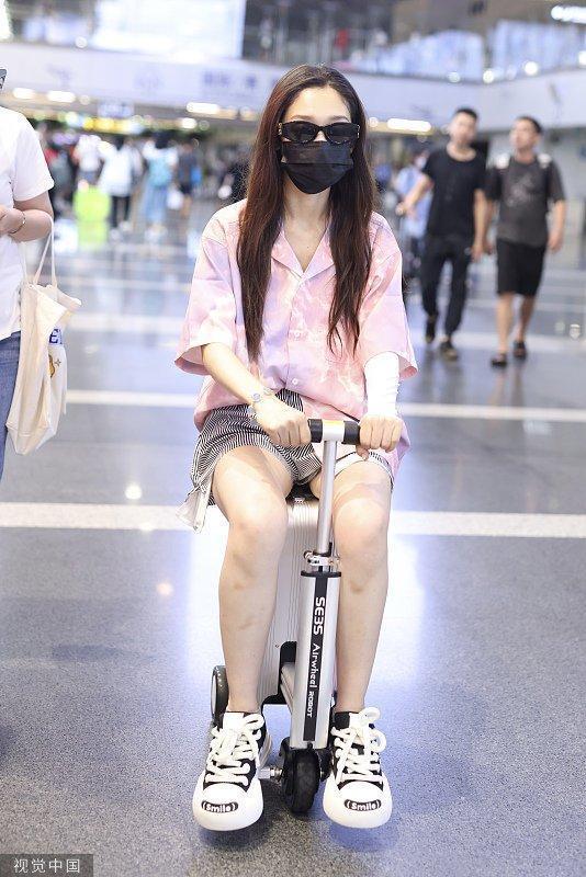 希林娜依·高粉色上衣搭超短热裤 骑代步车行李箱现身