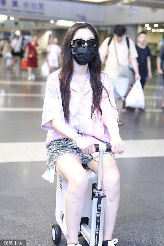 希林娜依·高粉色上衣搭超短热裤 骑代步车行李箱现身