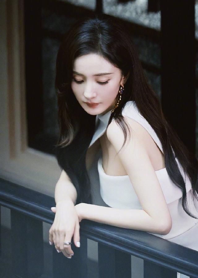 杨幂高开叉白色长裙莞尔动人，花团锦簇中显静谧之美