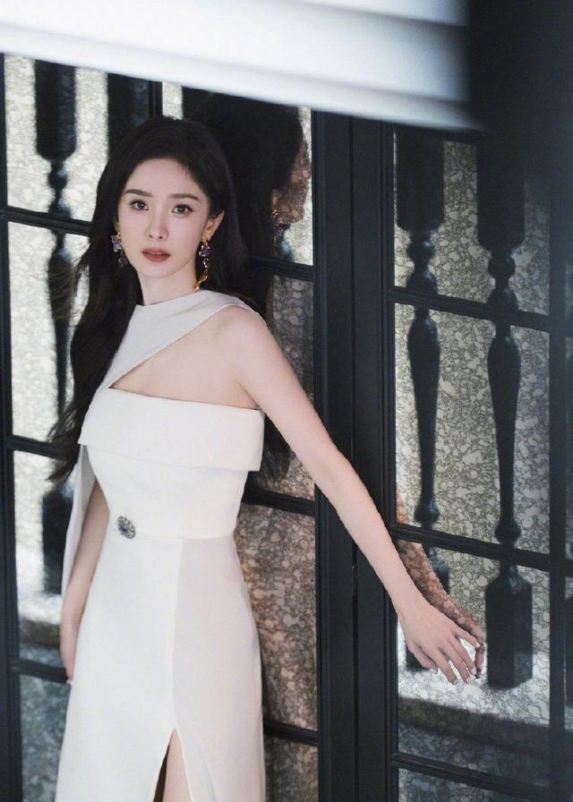 杨幂高开叉白色长裙莞尔动人，花团锦簇中显静谧之美