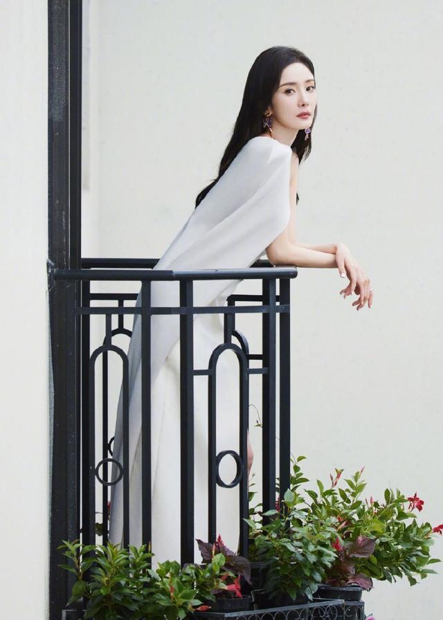 杨幂高开叉白色长裙莞尔动人，花团锦簇中显静谧之美