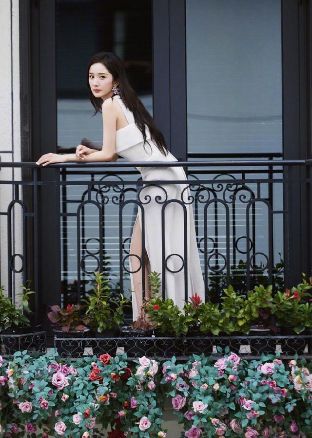 杨幂高开叉白色长裙莞尔动人，花团锦簇中显静谧之美